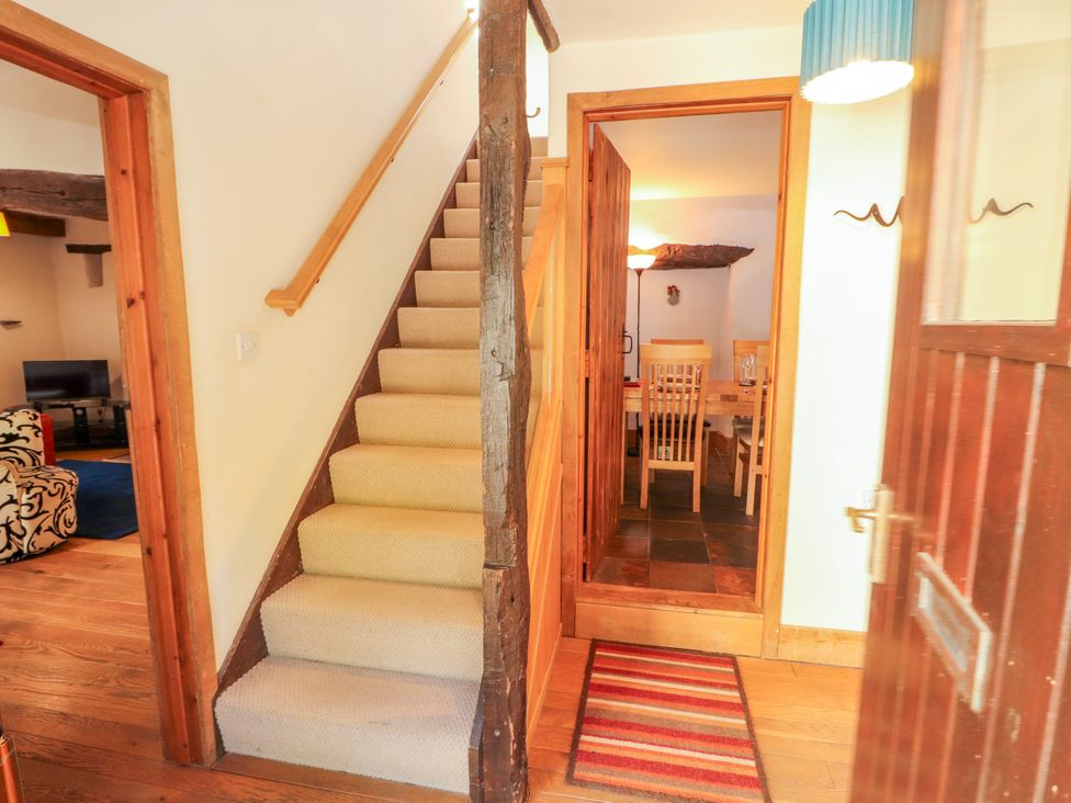 A hallway with stairs and a view into the dining area at Beck Edge in Braithwaite