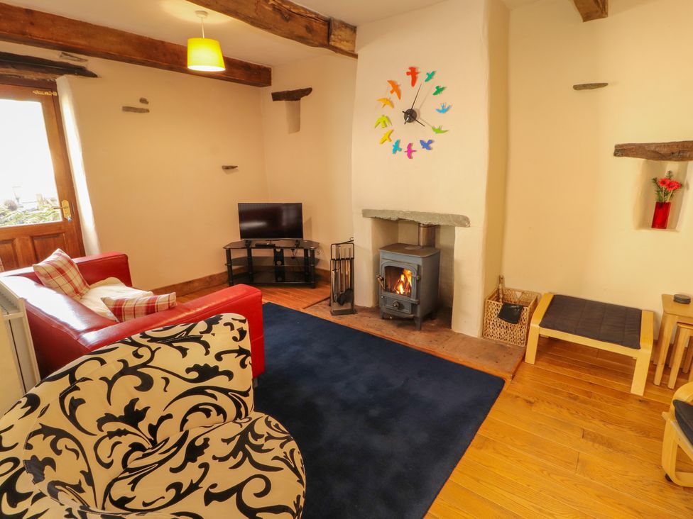 A living room with a wood stove and sofa at Beck Edge in Braithwaite