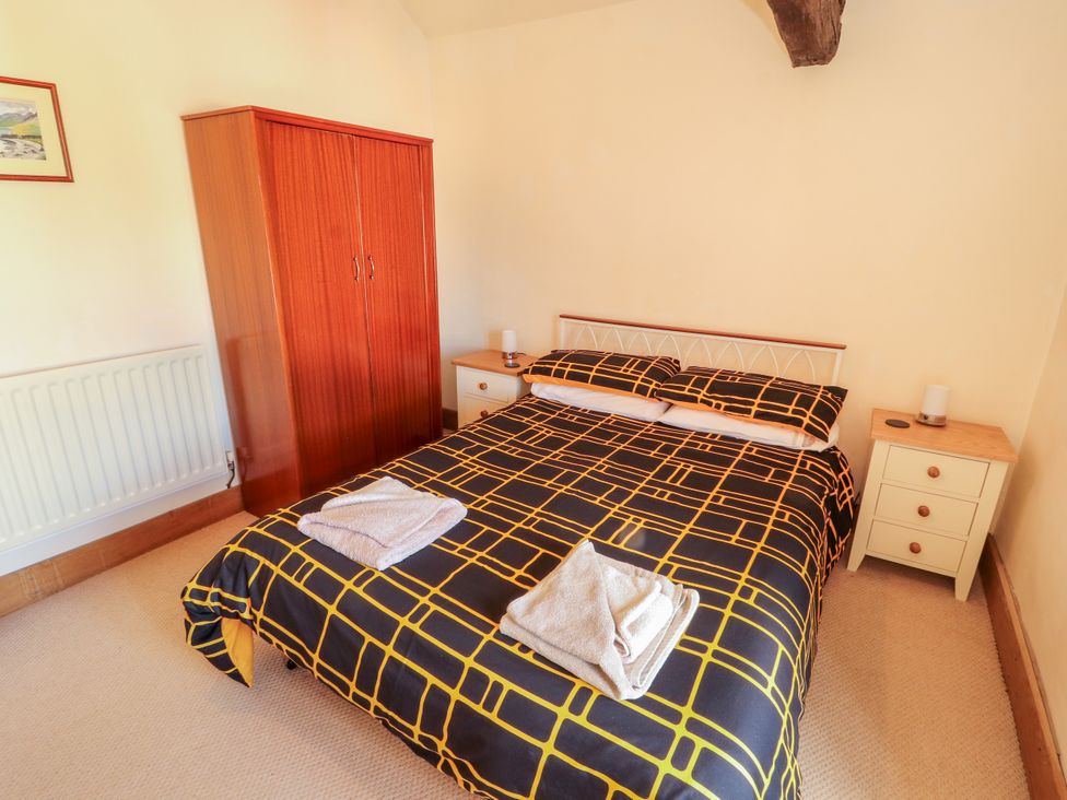 A bedroom with a bed, wardrobe, and bedside table at Beck Edge in Braithwaite