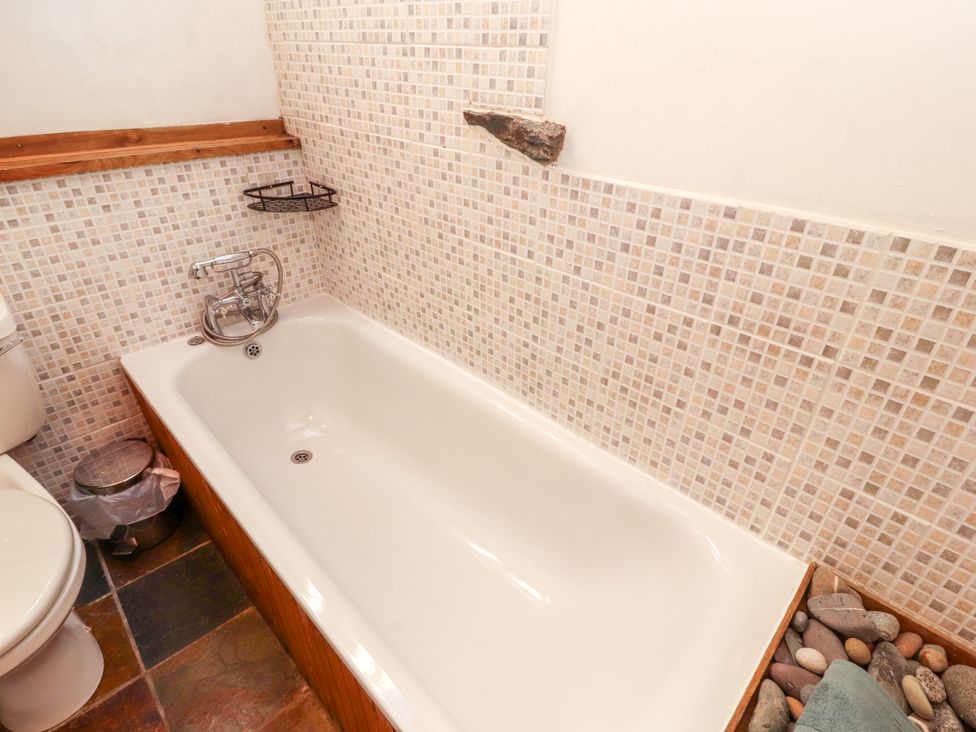 A bathroom with a bathtub and toilet at Beck Edge in Braithwaite