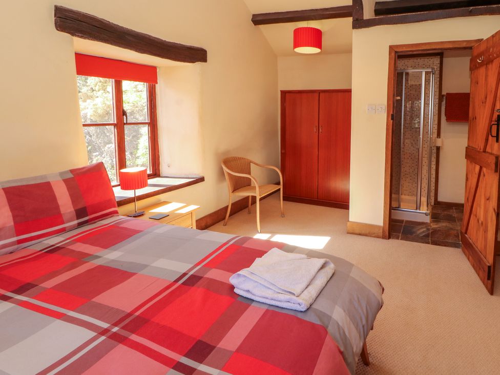 A bedroom with a bed, chair, and shower at Beck Edge in Braithwaite