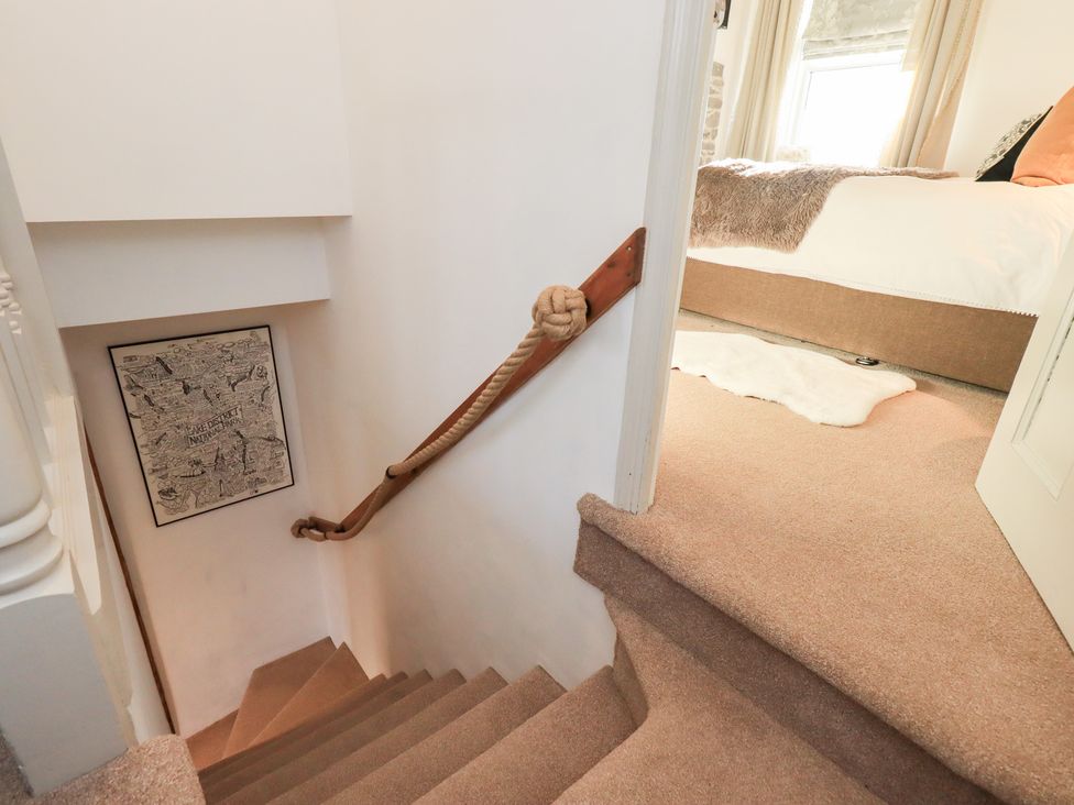 A staircase with rope railing and wall art at Gosling Cottage in Kendal