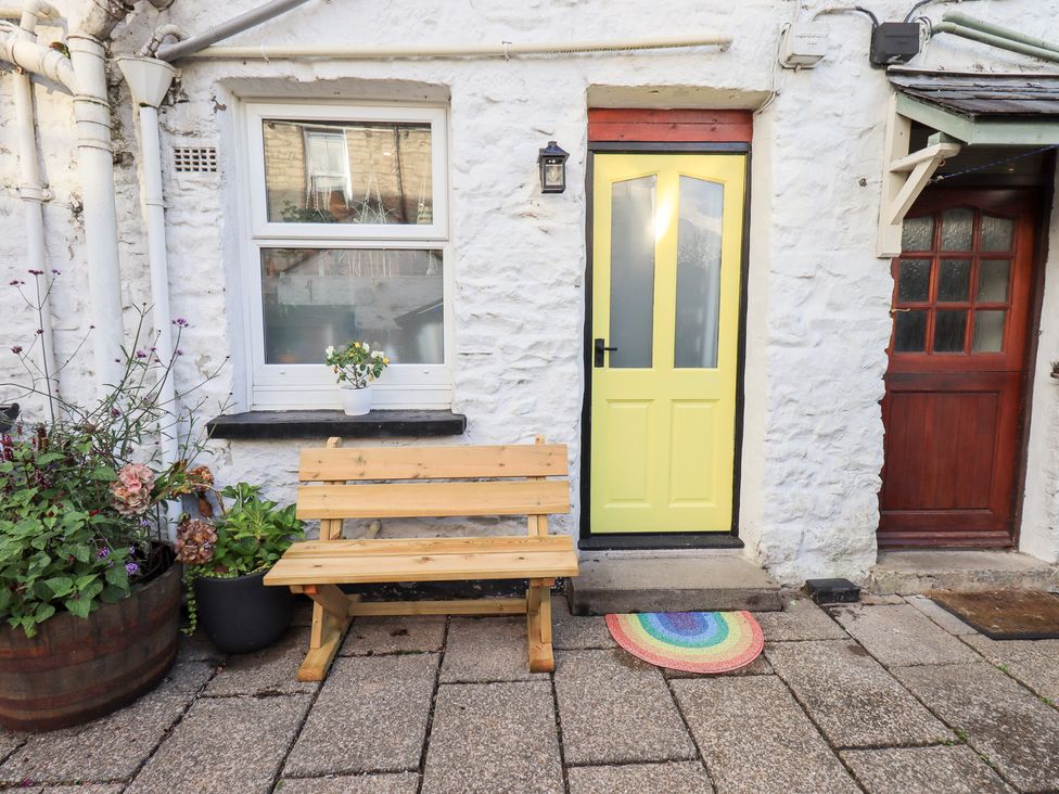 An outdoor area with a yellow door and wooden bench at Gosling Cottage in Kendal