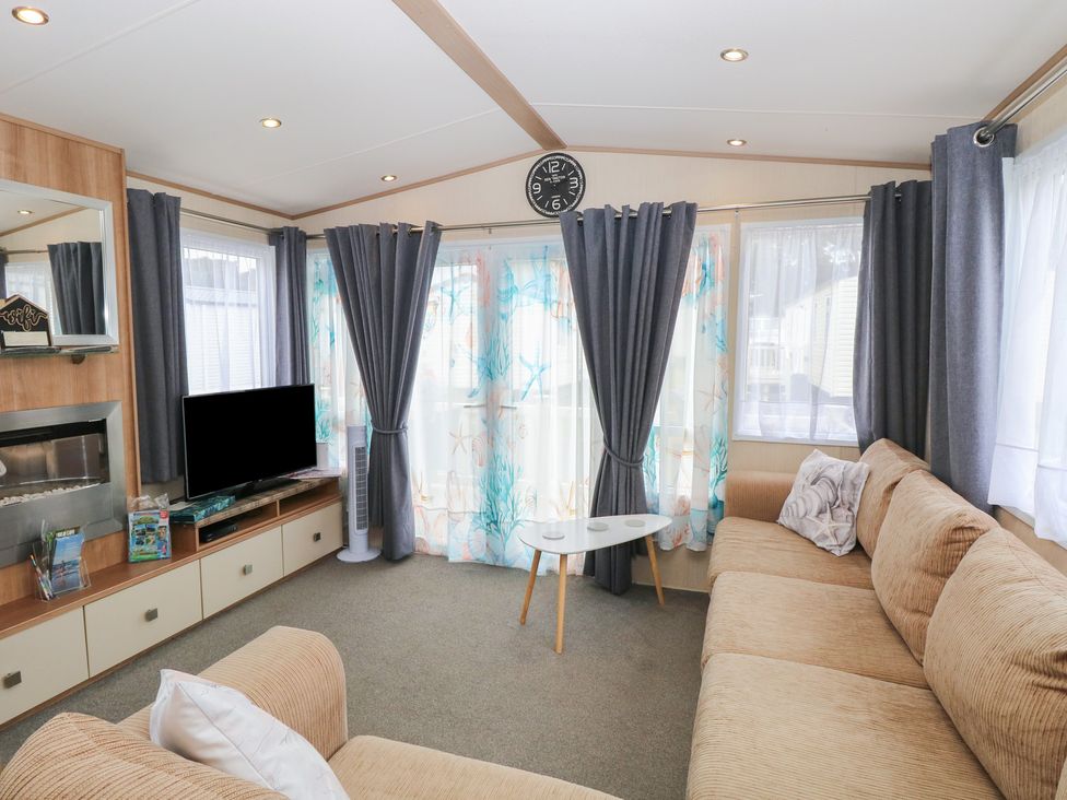 A living room with a television and sofa at Seashell Lodge, 50 Foxburrow Hang Belton, Norfolk