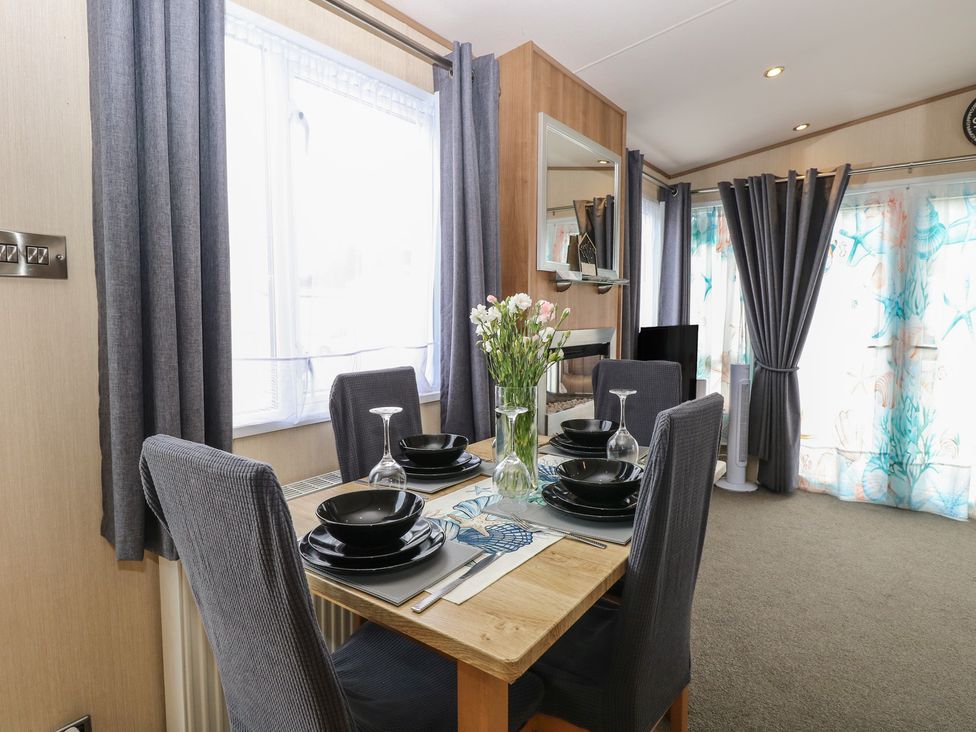 A dining room with a table set for four at Seashell Lodge, 50 Foxburrow Hang, Belton, Norfolk