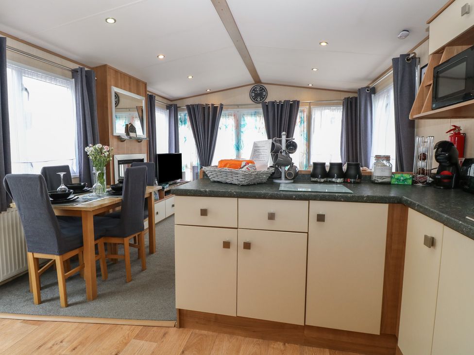 A kitchen with a dining table and chairs at Seashell Lodge, 50 Foxburrow Hang Belton, Norfolk