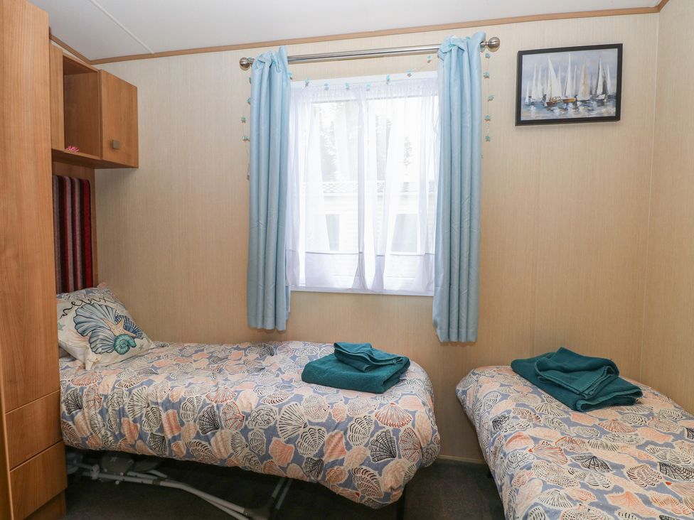 A bedroom with two beds and a window at Seashell Lodge, 50 Foxburrow Hang Belton, Norfolk
