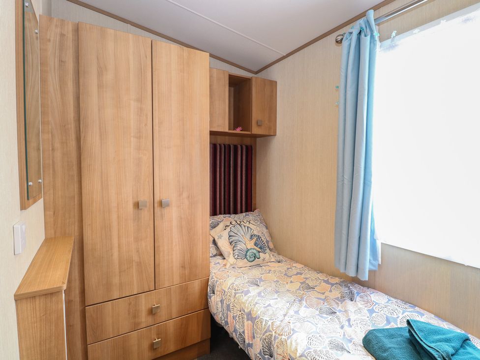 A bedroom with a bed and wardrobe at Seashell Lodge, 50 Foxburrow Hang, Belton, Norfolk