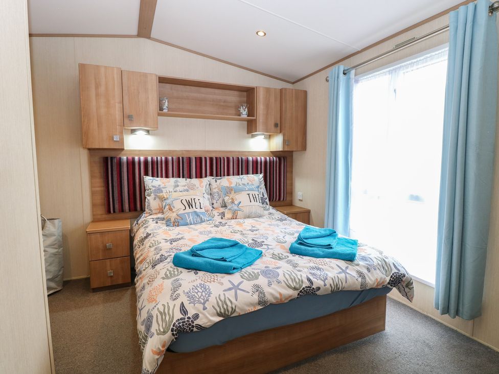 A bedroom with a bed and bedside table at Seashell Lodge, 50 Foxburrow Hang, Belton, Norfolk