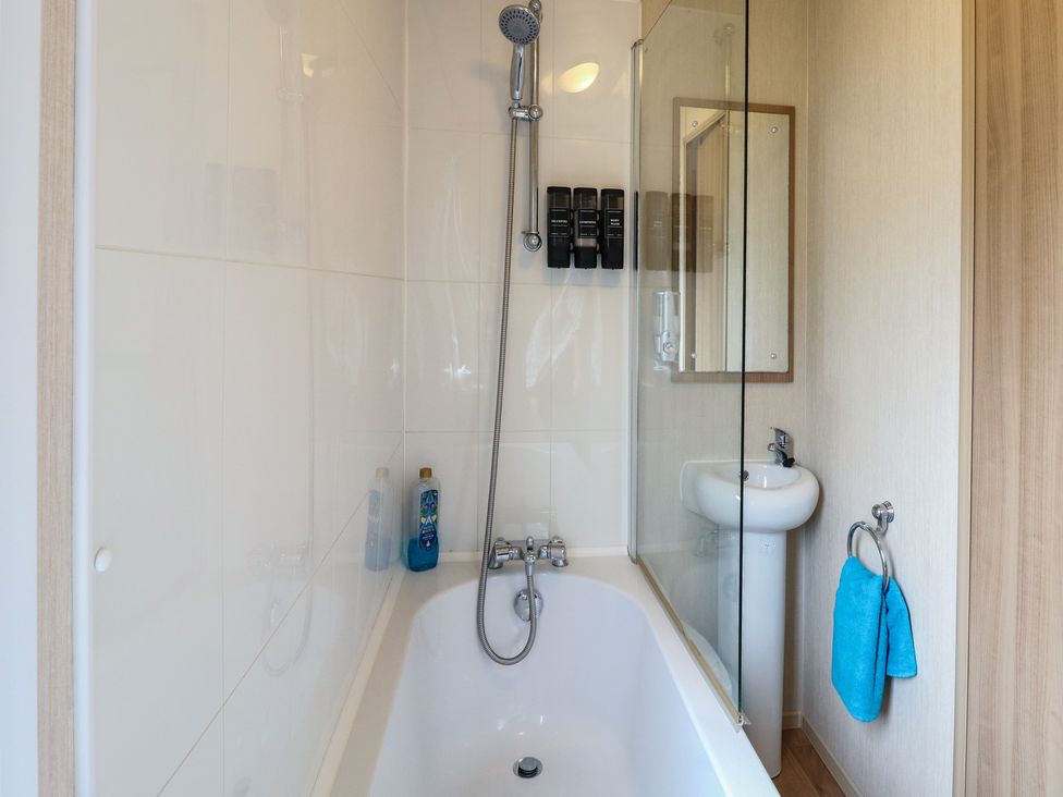 A bathroom with a bathtub and shower at Seashell Lodge, 50 Foxburrow Hang, Belton, Norfolk