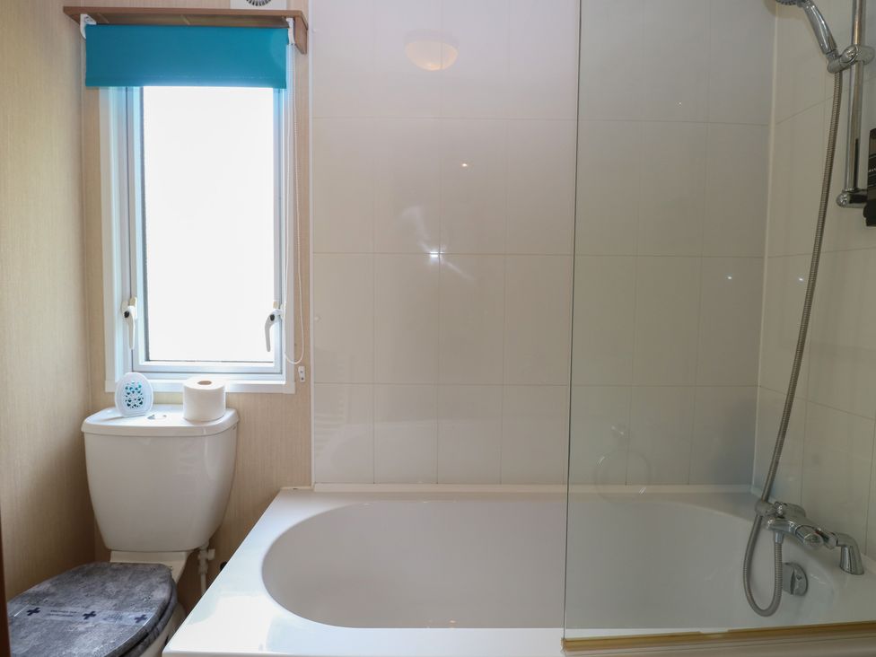 A bathroom with a bathtub and toilet at Seashell Lodge, 50 Foxburrow Hang Belton, Norfolk