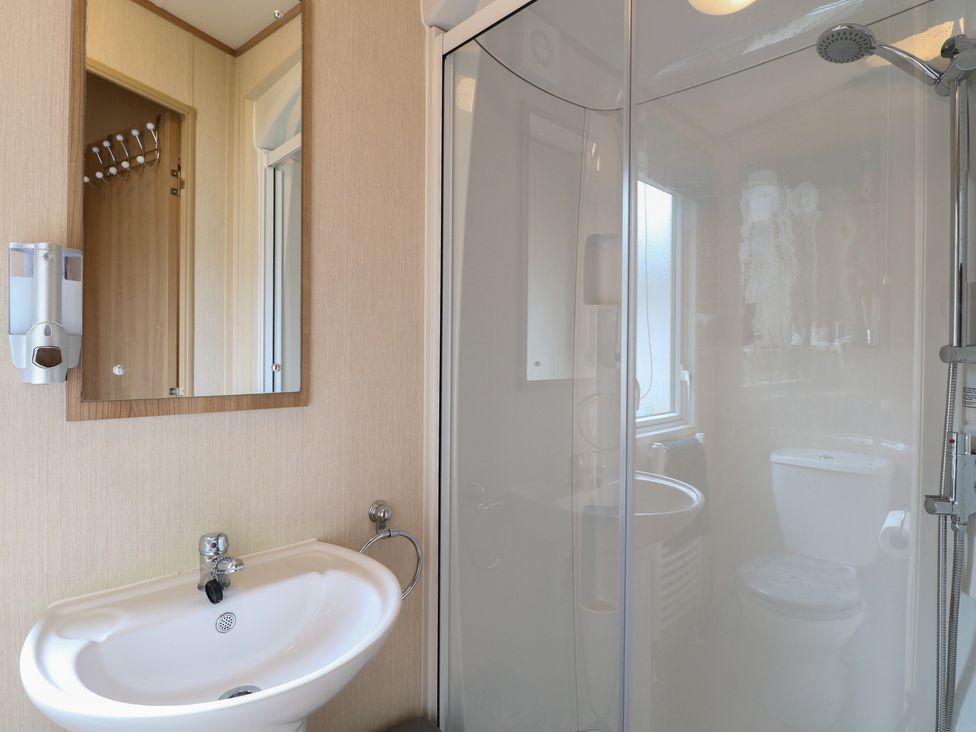 A bathroom with a sink, mirror, toilet, and shower at Seashell Lodge, 50 Foxburrow Hang, Belton, Norfolk