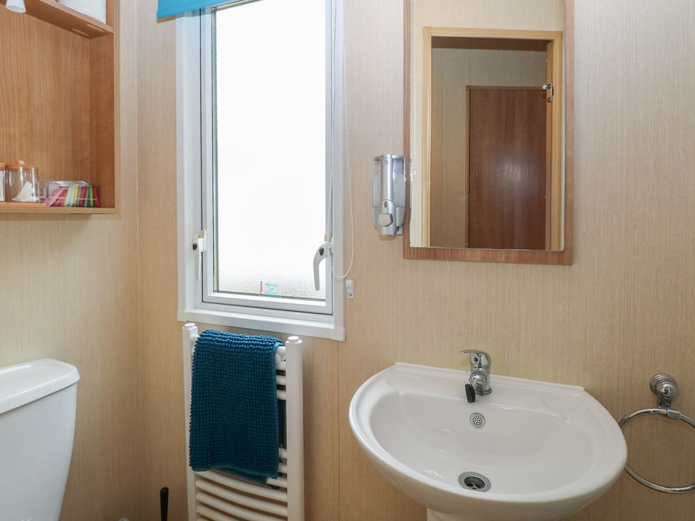 A bathroom with a toilet, sink and mirror at Seashell Lodge, 50 Foxburrow Hang, Belton, Norfolk
