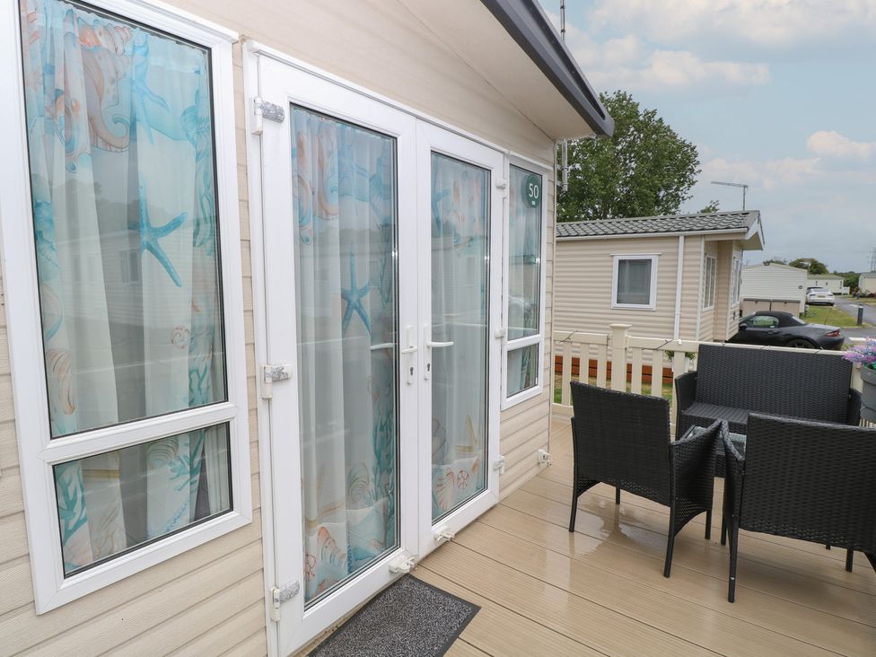 An outdoor area with double doors and a seating arrangement at Seashell Lodge, 50 Foxburrow Hang, Belton, Norfolk