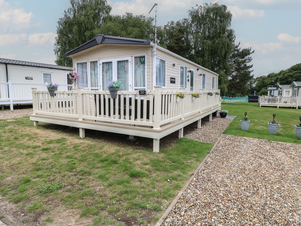 A mobile home with a deck and planters at Seashell Lodge, 50 Foxburrow Hang, Belton, Norfolk