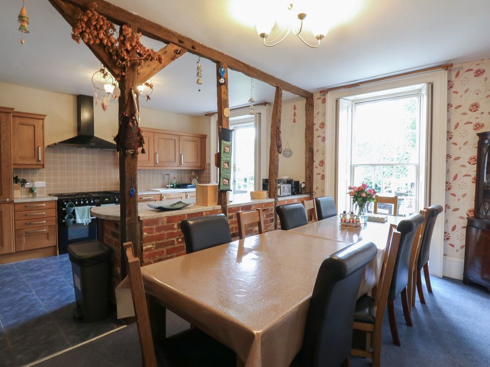A dining room with a large wooden table and kitchen adjacent at Chilton Manor House in Sittingbourne
