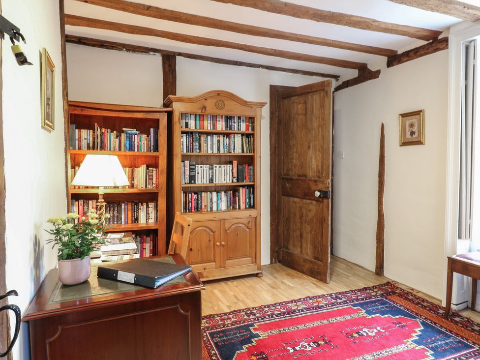 A snug with a bookshelf, lamp, and table at Chilton Manor House in Sittingbourne
