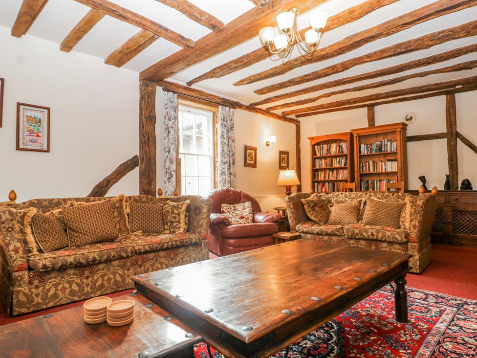 A living room with sofas, a wooden table, and a bookshelf at Chilton Manor House in Sittingbourne