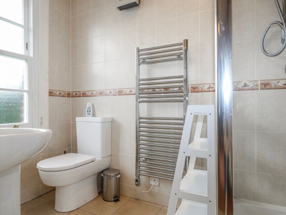 A bathroom with a sink, toilet, towel radiator, and step ladder at Chilton Manor House in Sittingbourne