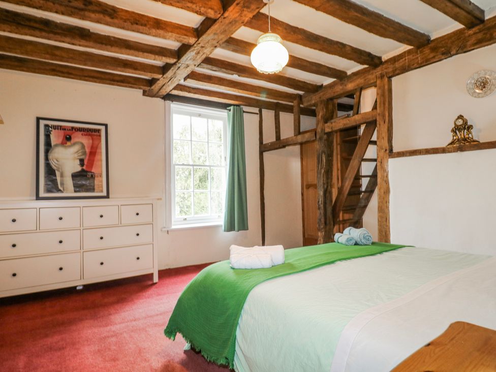 A bedroom with a bed, dresser, and staircase at Chilton Manor House in Sittingbourne