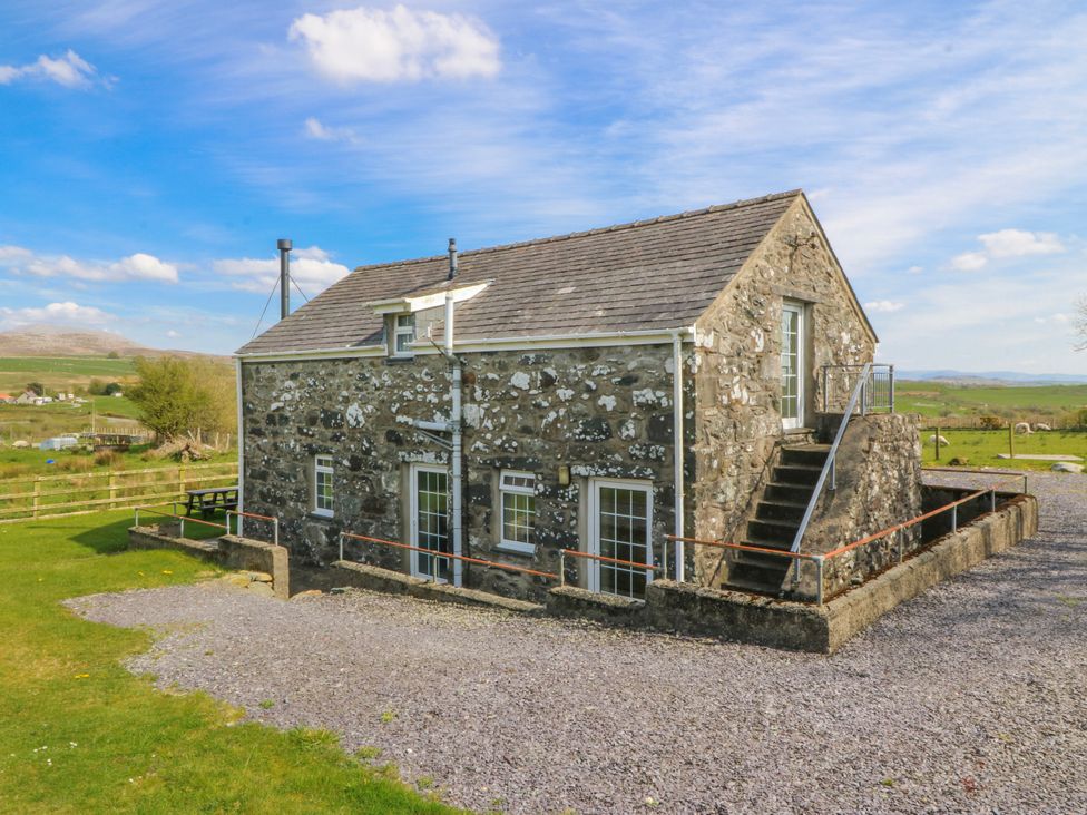 A stone building with a gravel area and stairs at Bwthyn Derwin Fawr in Garndolbenmaen near Penygroes
