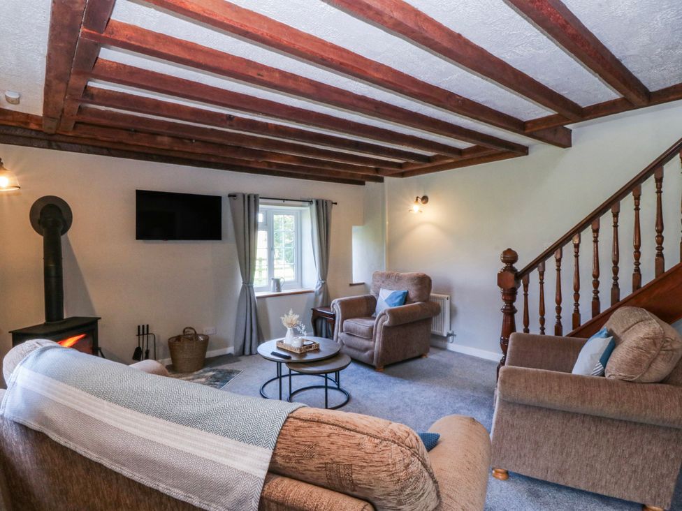 A living room with a stove and seating area at Bwthyn Derwin Fawr in Garndolbenmaen near Penygroes