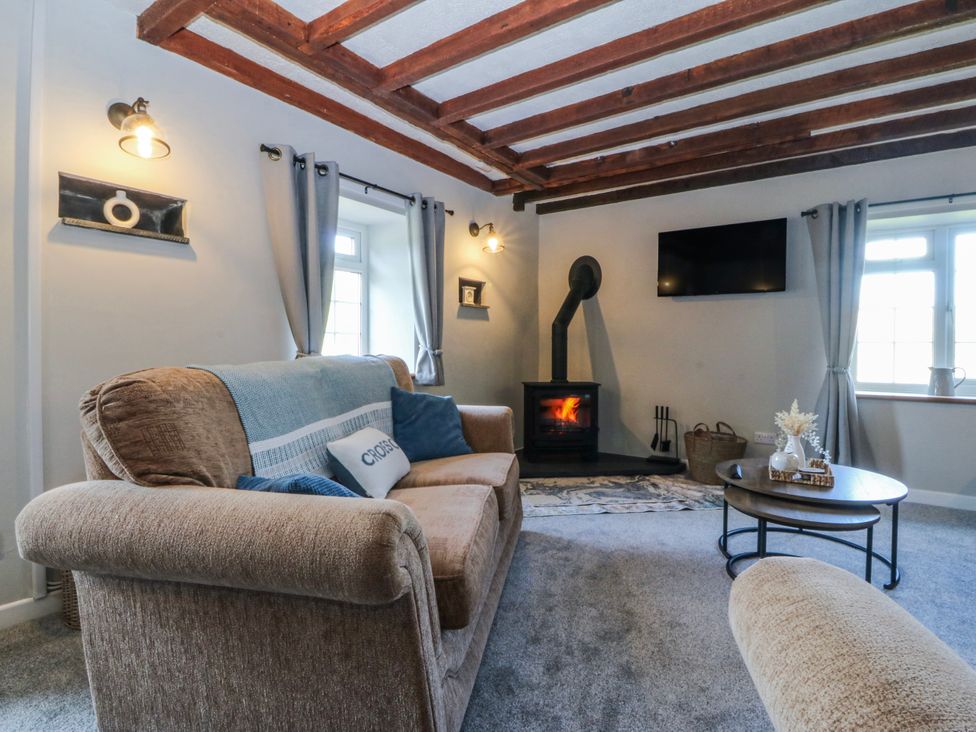 A living room with a sofa and fireplace at Bwthyn Derwin Fawr in Garndolbenmaen near Penygroes