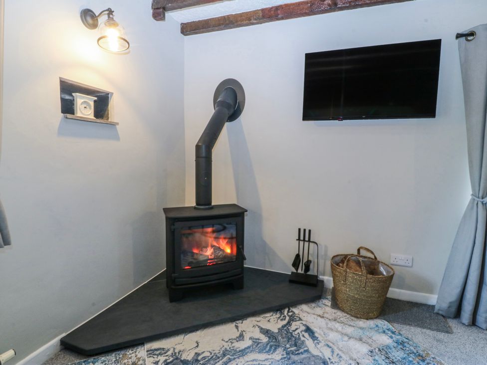 A snug with a fireplace and TV at Bwthyn Derwin Fawr in Garndolbenmaen near Penygroes