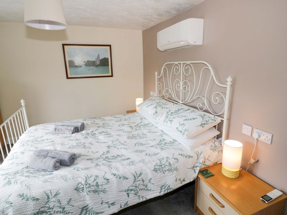 A bedroom with a bed, lamp, and painting at The Golden Cross Cottage in Evesham