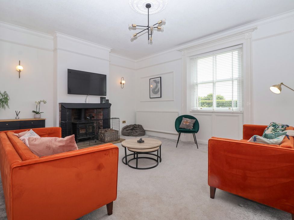 A living room with an orange sofa and coffee table at The Grange in Flamborough