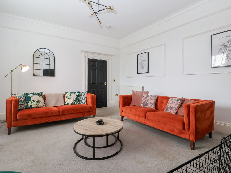 A living room with orange sofas and a round table at The Grange in Flamborough