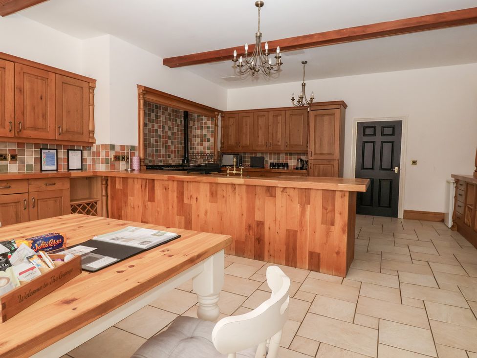 A kitchen with wooden cabinets and a dining table at The Grange in Flamborough