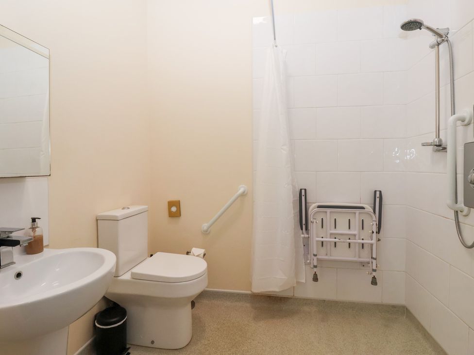 A bathroom with a sink, toilet, shower, and grab bars at The Grange in Flamborough