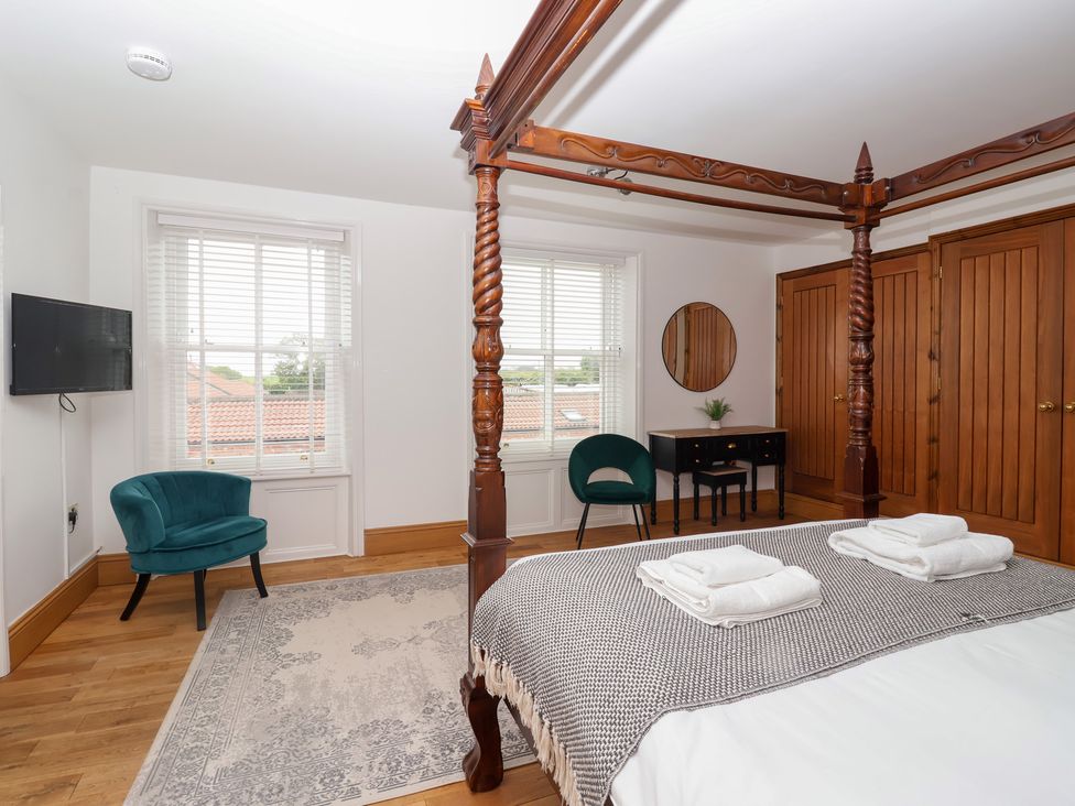 A bedroom featuring a four-poster bed and a desk at The Grange in Flamborough