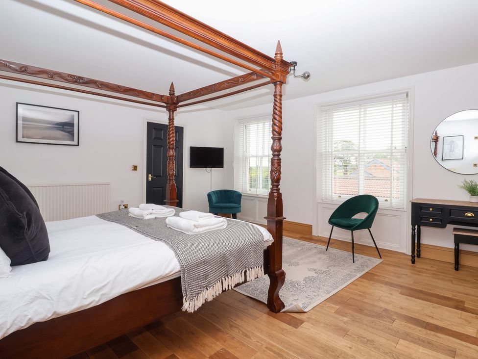 A bedroom with a four-poster bed and a television at The Grange in Flamborough