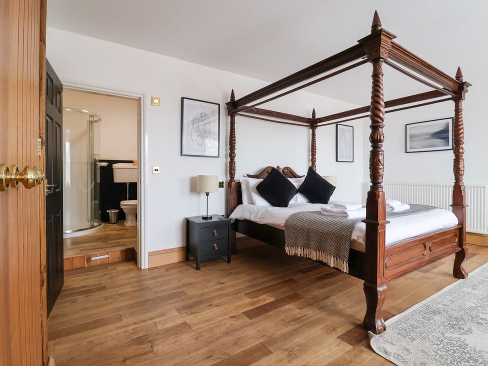 A bedroom with a four-poster bed and attached bathroom at The Grange in Flamborough