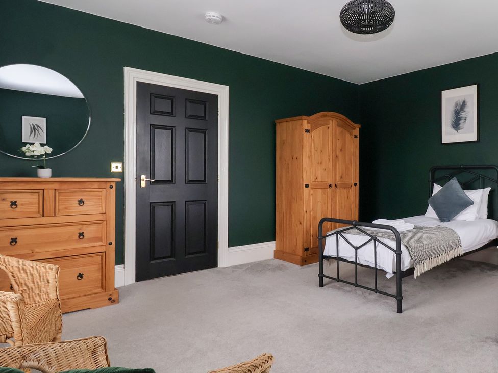 A bedroom with a bed, dresser, and wardrobe at The Grange in Flamborough