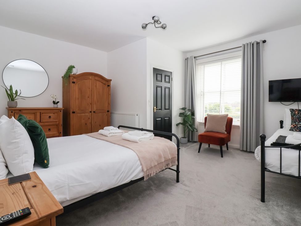 A bedroom with two beds, wardrobe, and television at The Grange in Flamborough