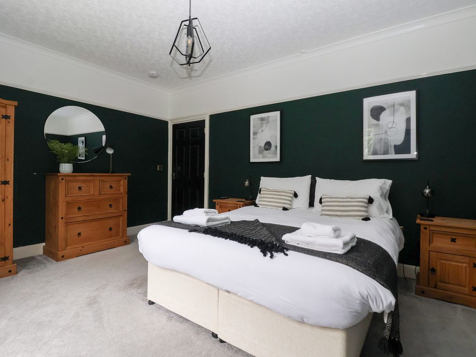 A bedroom with a bed, dresser, and wall art at The Grange in Flamborough