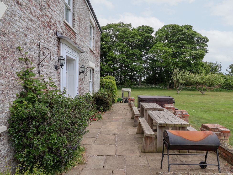 An outdoor dining area with a barbecue grill and table at The Grange in Flamborough