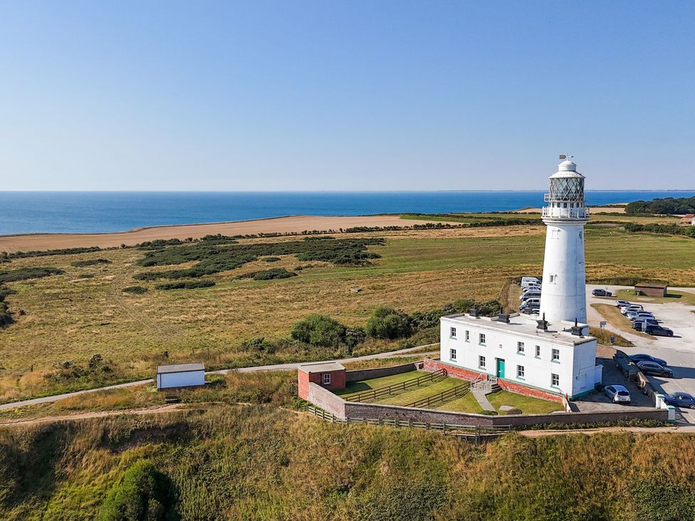 A lighthouse near the sea with a parking lot at The Grange in Flamborough