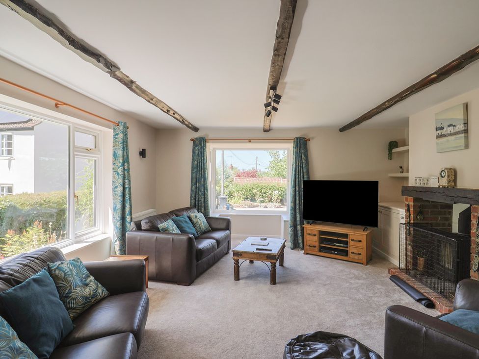 A living room with a sofa, coffee table, television, and windows at Woodstock in Chard