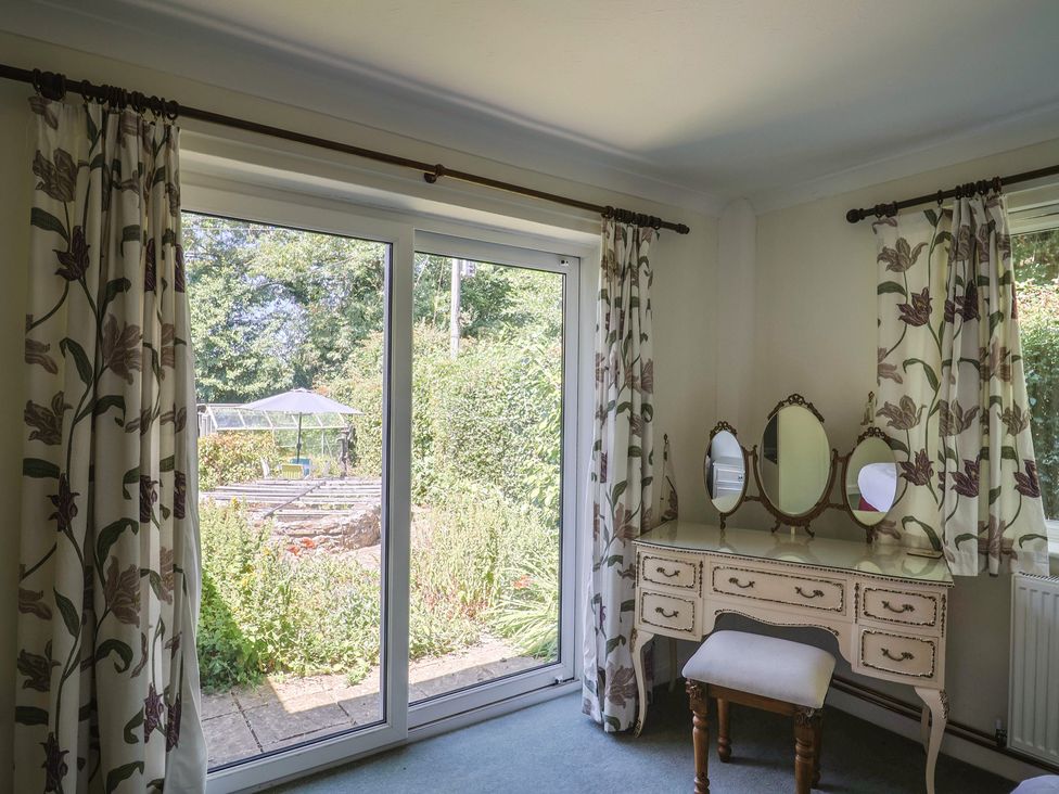 A bedroom with a vanity table and sliding doors overlooking a garden at Woodstock in Chard