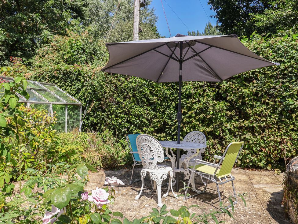 A table and chairs under an umbrella in the garden at Woodstock, Chard