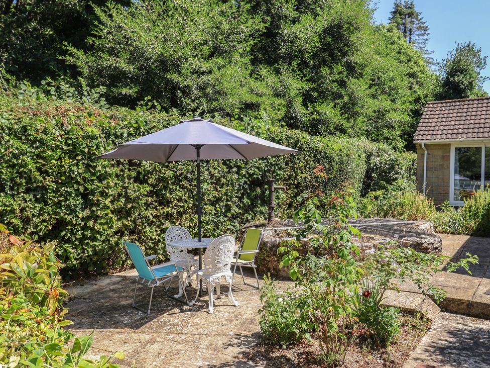 A garden with a table and chairs under an umbrella at Woodstock in Chard