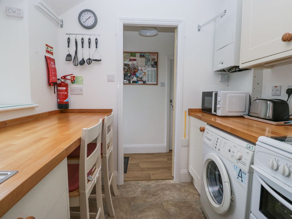 A kitchen with appliances and stools at 14 Castle Garth Kendal