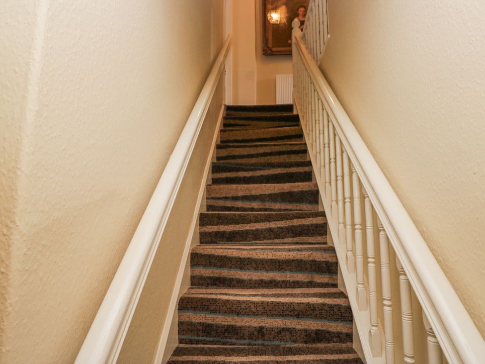 A staircase with a handrail and carpet at 14 Castle Garth in Kendal