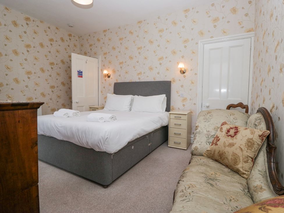 A bedroom with a double bed and a small sofa at 14 Castle Garth in Kendal