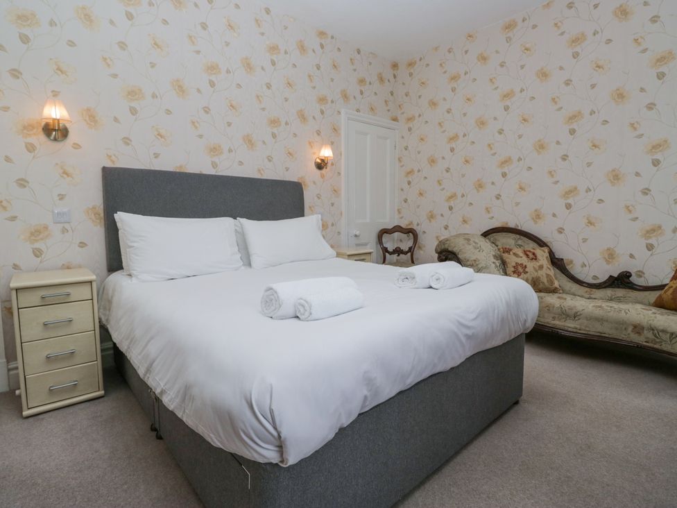 A bedroom with a bed and sofa at 14 Castle Garth Kendal