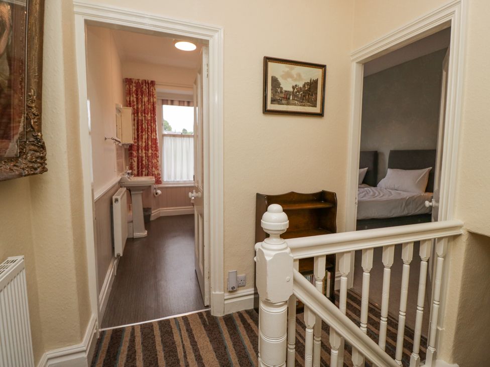 A hallway with a staircase and access to a bathroom and bedroom at 14 Castle Garth Kendal